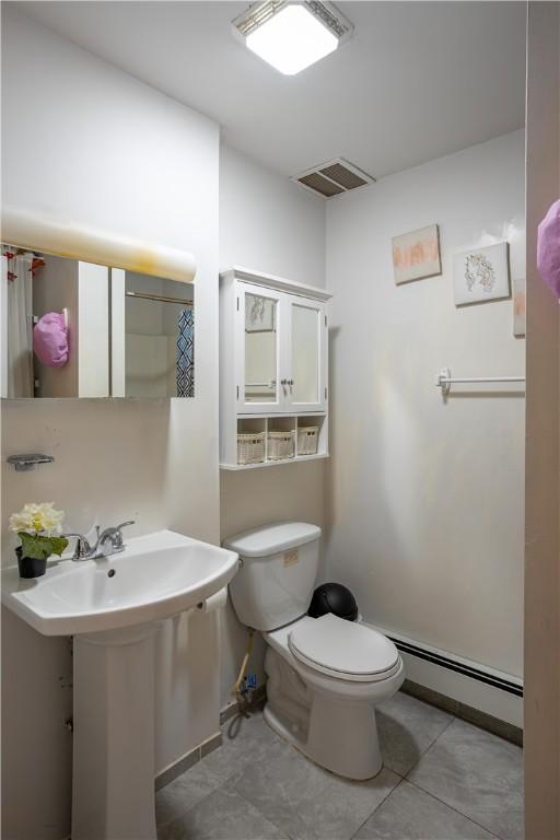 bathroom featuring a baseboard heating unit, toilet, tile patterned floors, and sink