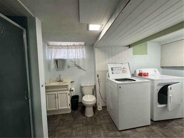 washroom featuring washing machine and dryer, dark parquet floors, and sink