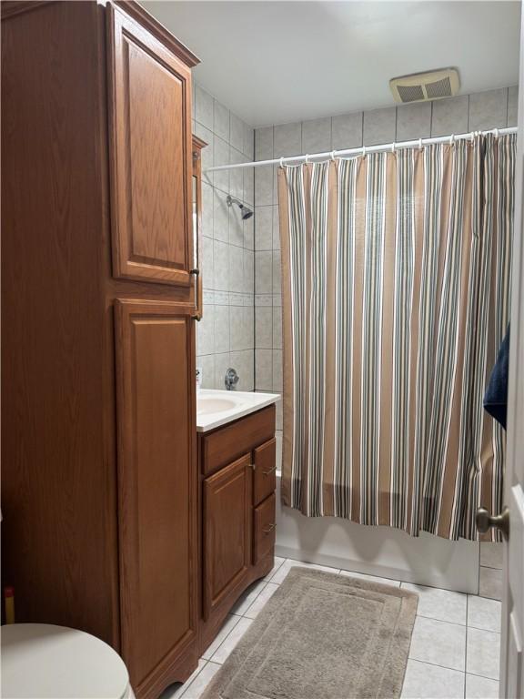 full bathroom featuring toilet, tile patterned floors, vanity, and shower / bathtub combination with curtain