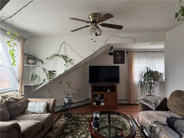 living room with dark wood-type flooring, a textured ceiling, a baseboard heating unit, and a healthy amount of sunlight