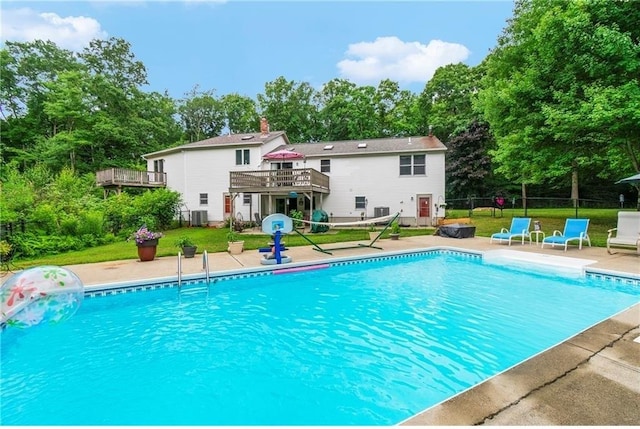 view of pool with a wooden deck, a yard, and central AC