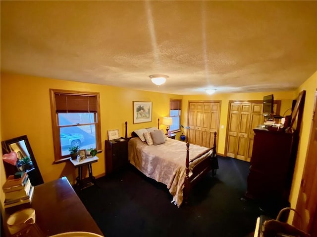 bedroom with a textured ceiling and multiple closets