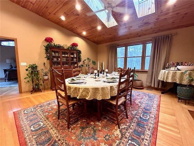 dining room with wood ceiling, lofted ceiling with skylight, and light hardwood / wood-style floors