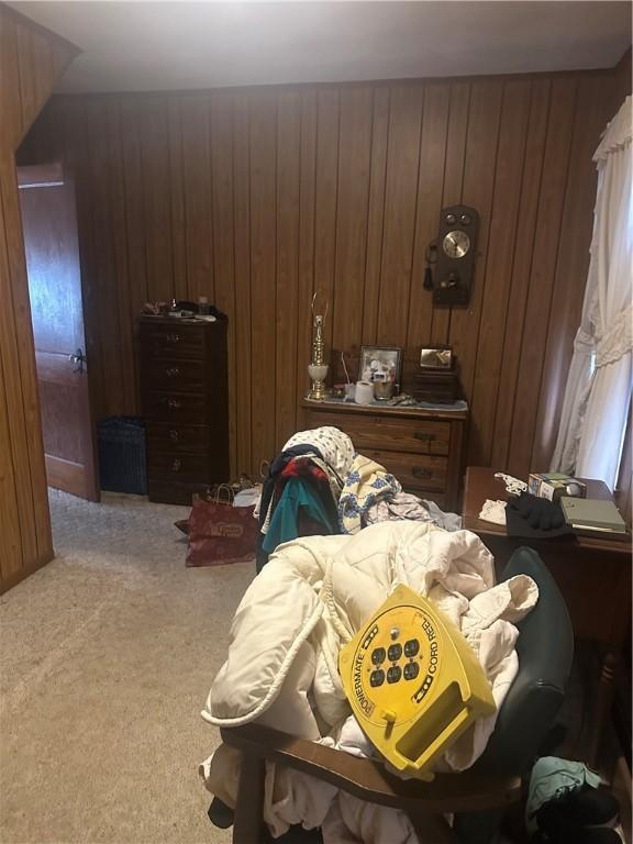 bedroom with light colored carpet and wooden walls