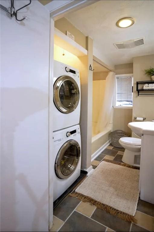 laundry area featuring stacked washer / drying machine and sink