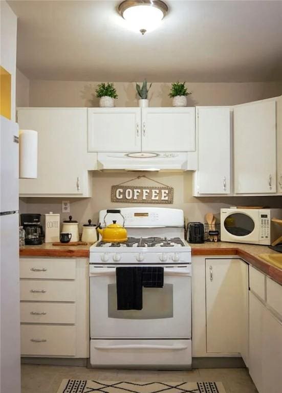 kitchen with light tile patterned floors, white cabinetry, butcher block counters, and white appliances