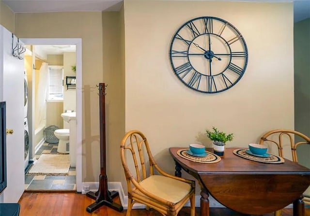 dining space featuring stacked washer and clothes dryer and wood-type flooring