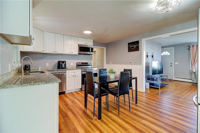 kitchen featuring white cabinets, appliances with stainless steel finishes, sink, and light wood-type flooring