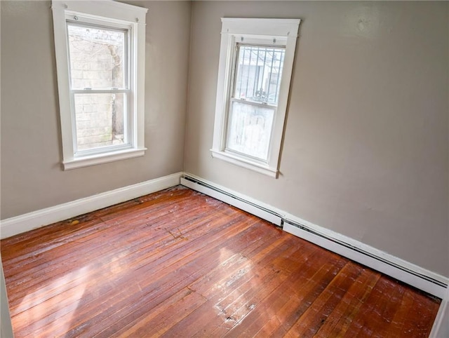 spare room featuring baseboard heating and light hardwood / wood-style flooring