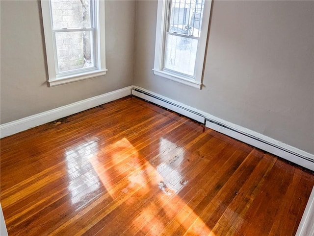 unfurnished room with baseboard heating and wood-type flooring