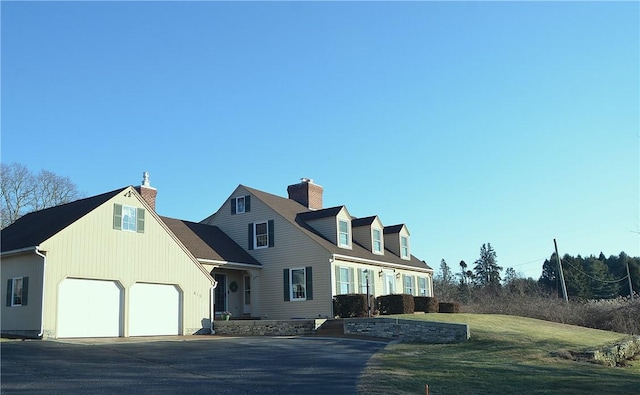 new england style home with a garage and a front lawn