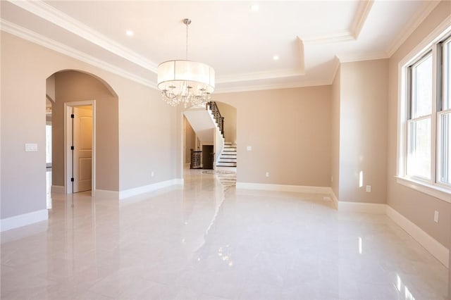 spare room featuring a tray ceiling, crown molding, and a notable chandelier