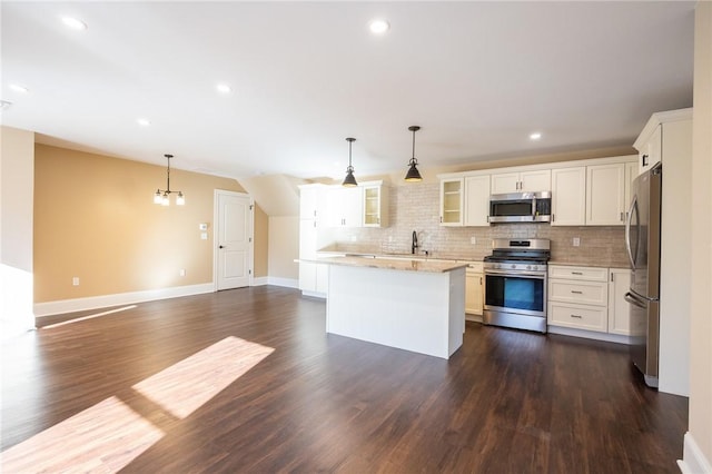 kitchen with hanging light fixtures, appliances with stainless steel finishes, white cabinetry, and a center island