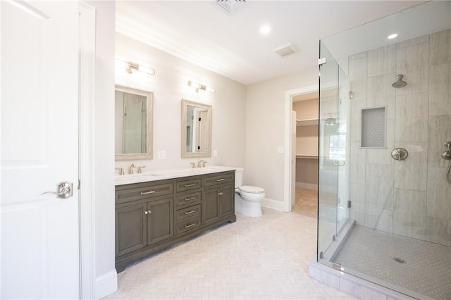 bathroom featuring a shower with shower door, toilet, and vanity