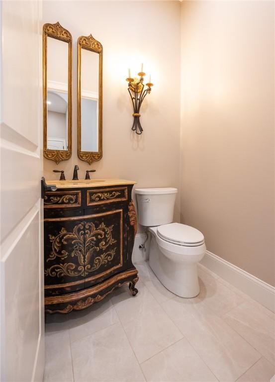 bathroom with toilet, vanity, and tile patterned flooring