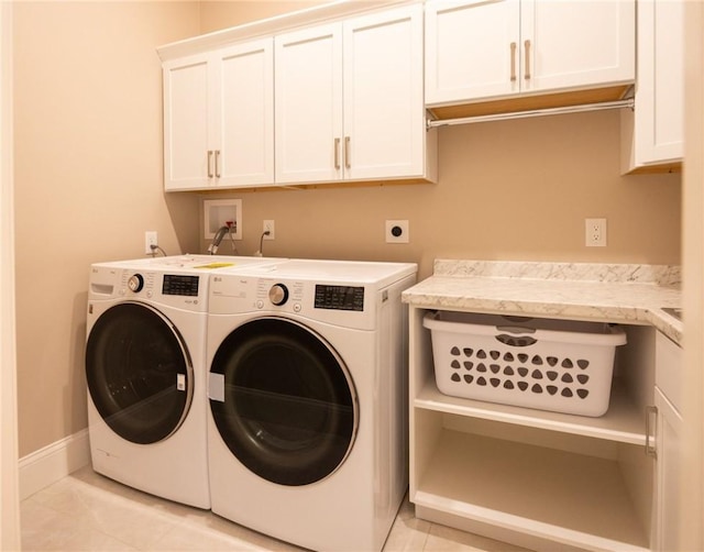 laundry room with cabinets, light tile patterned flooring, and washing machine and clothes dryer