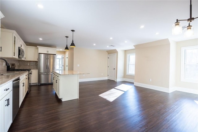 kitchen with white cabinetry, hanging light fixtures, stainless steel appliances, and a kitchen island