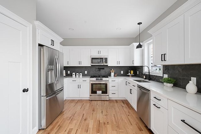 kitchen with tasteful backsplash, sink, hanging light fixtures, appliances with stainless steel finishes, and white cabinets