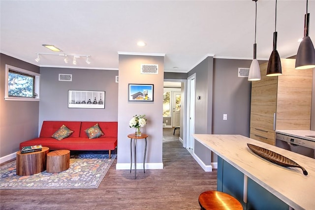 living room featuring dark hardwood / wood-style flooring, track lighting, and ornamental molding