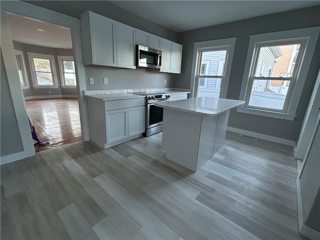 kitchen with light hardwood / wood-style floors, white cabinetry, a center island, and stainless steel appliances