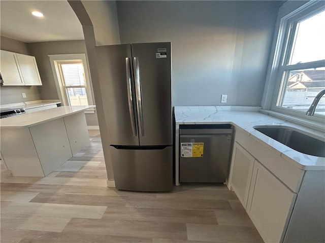 kitchen featuring dishwashing machine, white cabinetry, sink, stainless steel fridge, and kitchen peninsula