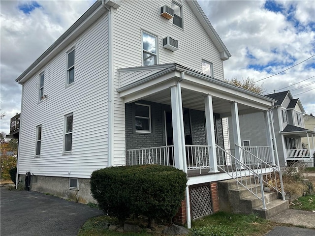 view of home's exterior featuring covered porch and a wall mounted AC