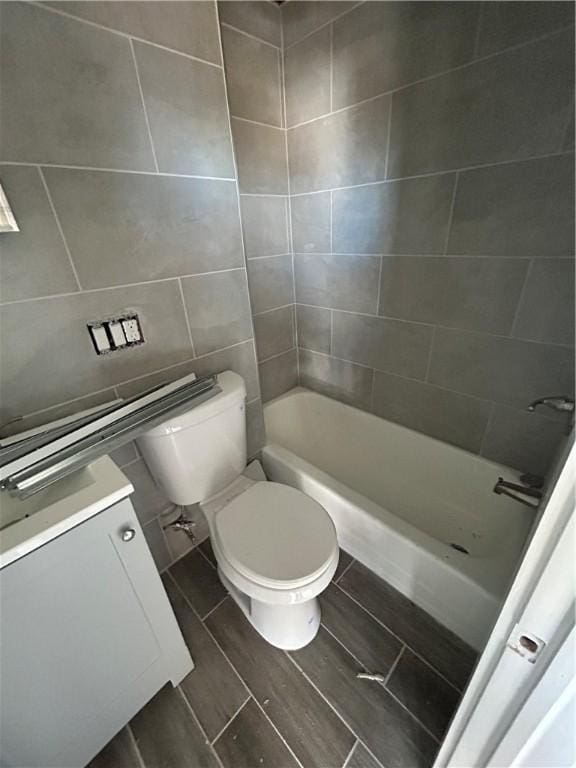 bathroom with toilet, tile walls, and vanity