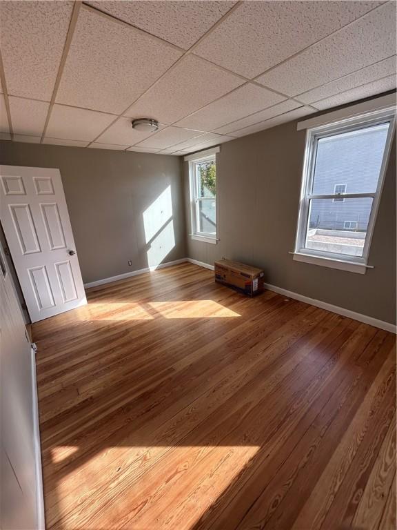 unfurnished room with a drop ceiling and hardwood / wood-style flooring