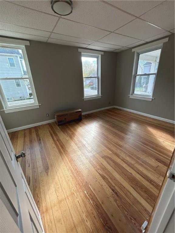 unfurnished room with a drop ceiling and hardwood / wood-style floors