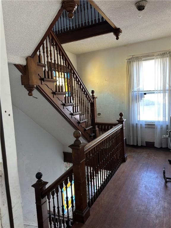 stairs with wood-type flooring and a textured ceiling