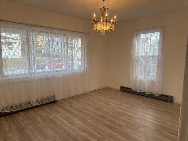 unfurnished room featuring an inviting chandelier, hardwood / wood-style floors, and baseboard heating