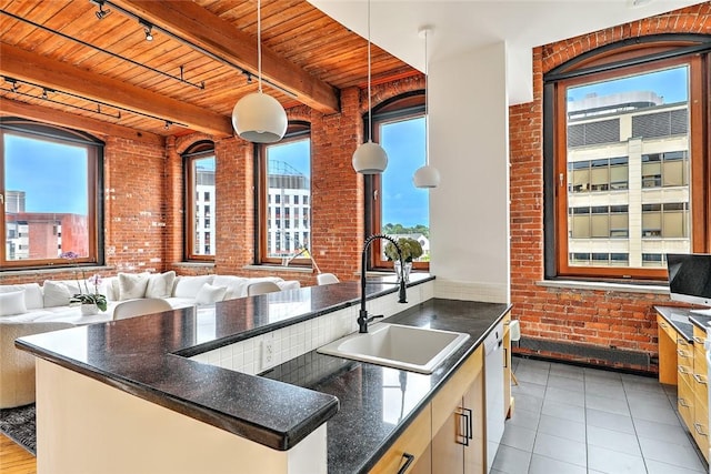 kitchen with brick wall, dishwasher, hanging light fixtures, and beamed ceiling