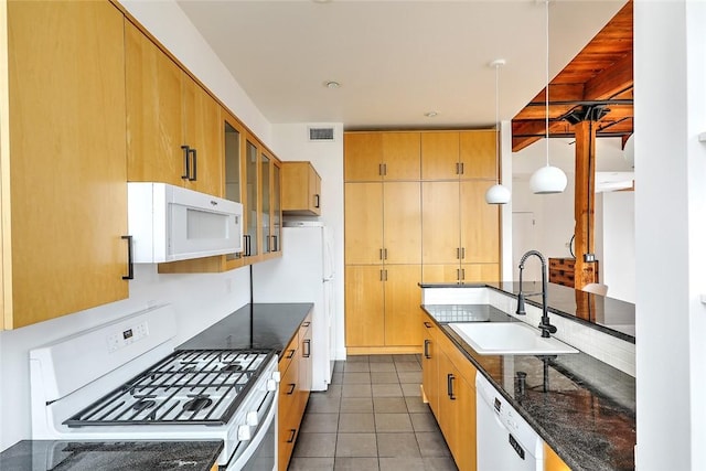 kitchen with white appliances, sink, dark stone counters, pendant lighting, and dark tile patterned floors