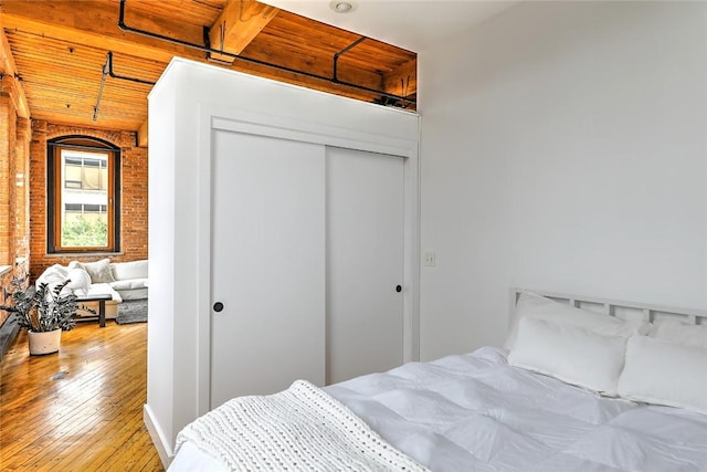 bedroom with a closet, wood ceiling, and light hardwood / wood-style flooring