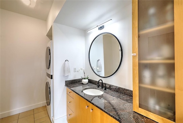 bathroom with stacked washing maching and dryer, tile patterned flooring, and vanity