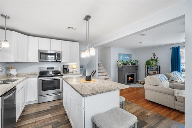 kitchen featuring white cabinetry, pendant lighting, a center island, and stainless steel appliances