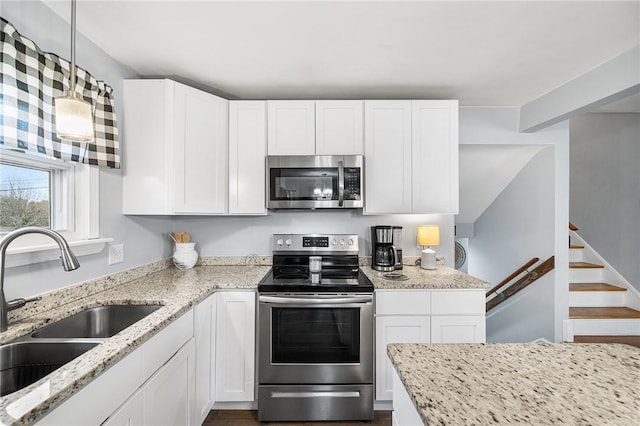 kitchen featuring stainless steel appliances, white cabinets, hanging light fixtures, and sink