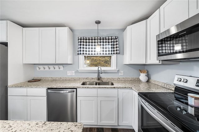 kitchen featuring hanging light fixtures, appliances with stainless steel finishes, sink, and white cabinetry