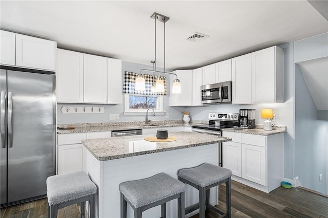 kitchen featuring a kitchen island, pendant lighting, sink, appliances with stainless steel finishes, and white cabinets