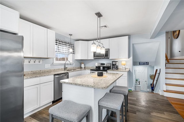 kitchen with a center island, pendant lighting, sink, white cabinetry, and stainless steel appliances