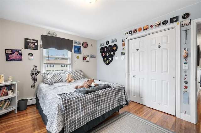 bedroom with a closet, wood-type flooring, and a baseboard radiator