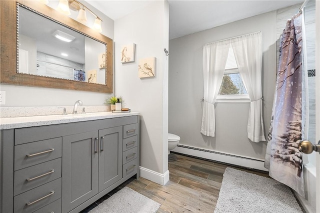 bathroom with a baseboard radiator, hardwood / wood-style floors, toilet, and vanity