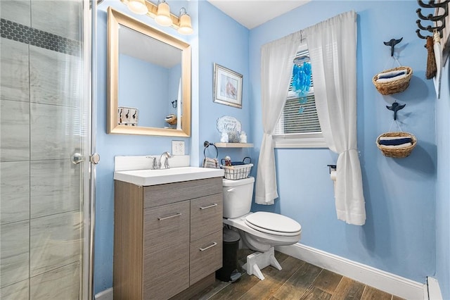 bathroom featuring toilet, a shower with shower door, vanity, and a baseboard radiator