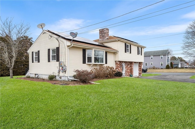 view of front of property featuring a front lawn, solar panels, and a garage