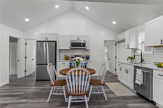 kitchen with sink, dark wood-type flooring, stainless steel appliances, high vaulted ceiling, and white cabinets