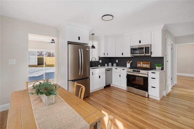 kitchen featuring appliances with stainless steel finishes, white cabinets, hanging light fixtures, and sink