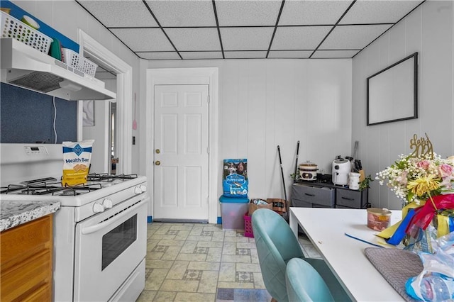 kitchen with a paneled ceiling, white gas range oven, and extractor fan