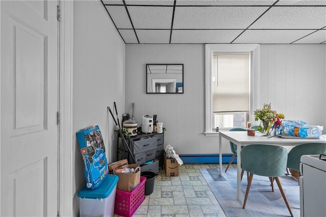 interior space with a healthy amount of sunlight, baseboard heating, and a drop ceiling