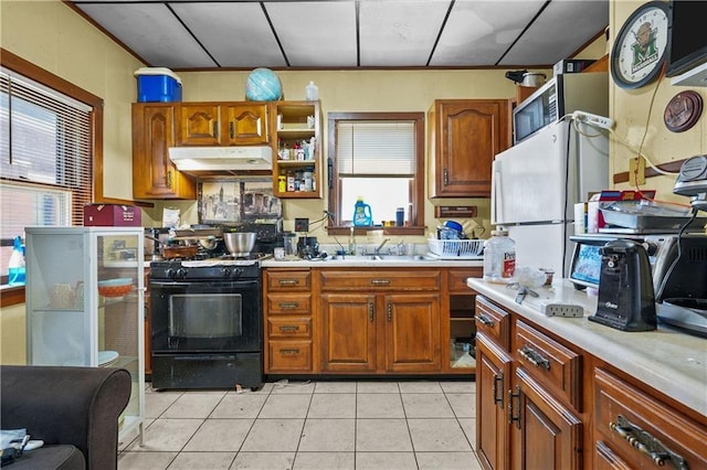 kitchen with sink, light tile patterned flooring, white fridge, and black range with gas cooktop