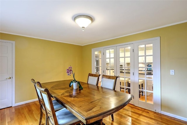 dining room with crown molding, light hardwood / wood-style floors, and french doors